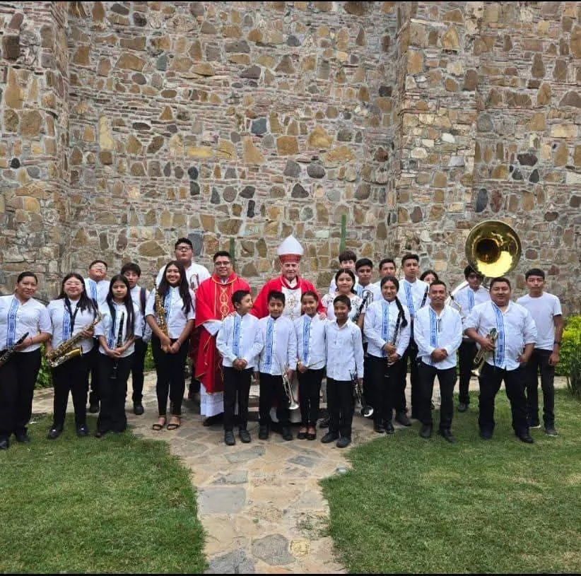 Integrantes de la Banda Filarmónica Infantil de Santo Tomás Jalieza con sus instrumentos frente al templo
